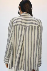 Camisa de corte oversize confeccionada en mezcla de viscosa, con estampado de rayas verticales. Presenta cuello solapa, cierre frontal con botones y mangas largas con puños amplios.