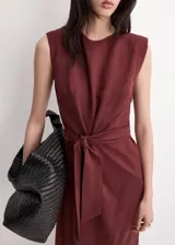 Vestido midi color bordó con cuello redondo, sin mangas y corte recto, con detalle de nudo y lazo ajustable en la cintura.