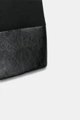 Vestido mini negro sin mangas, de cuello redondo, con detalle de tejido efecto piel combinado a tono en el bajo. Cuenta con forro interior y cierre en la espalda con cremallera oculta.