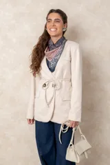 Chaquetón color beige de corte recto y largo, con cierre frontal mediante botones y lazo ajustable en la cintura. Presenta cuello en V, bolsillos laterales con solapa y mangas largas.