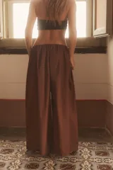 Pantalón negro de tiro medio, estilo culotte, con cintura elástica fruncida y piernas muy anchas. Posee bolsillos laterales ocultos.
