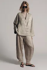 Blazer de estilo oriental confeccionado en hilatura de viscosa con tejido jacquard tono sobre tono. Presenta escote en pico, manga larga y cierre frontal cruzado con alamares a tono.