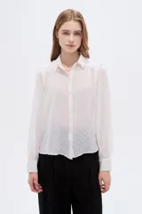 Camisa negra de poliéster con detalles de lurex y textura en relieve, corte holgado, mangas largas con puños y cierre frontal con botones.