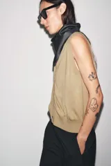 Chaleco de tejido de punto color camel, con escote en V y cierre frontal de botones oscuros.