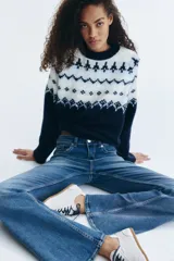 Jean de denim azul con leve stretch, corte ajustado de cintura a cadera y acampanado desde la rodilla al bajo. Modelo de tiro bajo con cierre y botón, bolsillos delanteros abiertos y bolsillos traseros con solapa y botón.