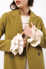 Buzo de tejido acanalado color lila, con cuello redondo decorado con dos volados y mangas largas con tres volados pequeños en los puños.