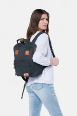 Mochila de lona gris oscuro con detalles en cuero sintético marrón, asas superiores y bolsillo frontal con cierre.