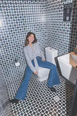 Jeans de corte flare y tiro medio, en color azul, con diseño acampanado y detalles de costuras en las piernas.
