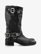 Bota de caña media de cuero negro, estilo biker, con caña arrugada y detalles de correas con hebillas metálicas plateadas en la parte superior y alrededor del tobillo. Posee un taco bajo y grueso.