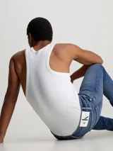 Jeans de hombre, talle bajo, corte slim ajustado, confeccionados en denim azul medio vintage con efecto desgastado. Presentan bragueta con cremallera y diseño de cinco bolsillos.