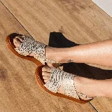 Sandalias de cuero color blanco con textura tipo reptil, plataforma marrón y hebilla metálica plateada.