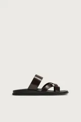 Sandalias de cuero marrón oscuro, con diseño de múltiples tiras cruzadas y separación para el dedo, montadas sobre una suela plana negra con horma anatómica.