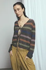 Cardigan de punto marrón con escote en V y cierre frontal con tiras para atar. Presenta diseño de rayas horizontales con patrón en zigzag de colores vibrantes como naranja, verde lima, azul y rosado.