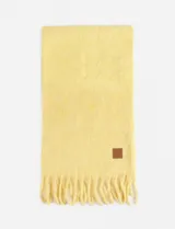 Bufanda rectangular color amarillo con flecos en los extremos y etiqueta de cuero sintético con logo en una esquina.