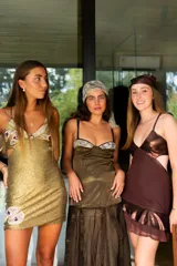 Vestido corto de fiesta color plateado con acabado brillante. Presenta un diseño de dos piezas que simula un conjunto de top y pollera, con aberturas laterales en la cintura, escote en V y tirantes finos que se cruzan en la espalda.