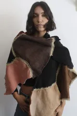 Ruana artesanal confeccionada con piezas de napalán de diversos colores unidas mediante costuras de crochet. Presenta un diseño tipo patchwork con texturas de cuero y gamuza, con bordes irregulares.