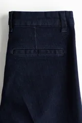 Jean acampanado de tiro alto en color azul marino, confeccionado en denim suave con leve elasticidad. Cuenta con cierre frontal y botón metálico.