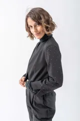 Chaqueta negra con cuello solapa, corte irregular y mangas largas con apliques de strass.