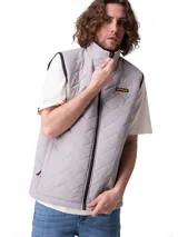 Chaleco acolchado gris Caterpillar con cierre frontal, cuello alto y bolsillos laterales. Presenta costuras en chevron y parche con el logo de la marca en el pecho.