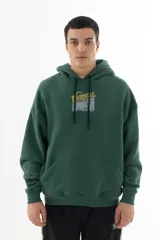 Buzo hoodie verde oscuro con estampa serigráfica frontal de alta definición con una escena urbana en estilo puntillista y logo VERNAL con efecto dorado envejecido. Corte oversize con hombros caídos, capucha doble y bolsillo canguro.