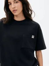 Camiseta de manga corta color blanco hueso, con cuello redondo y bolsillo de parche en el pecho.