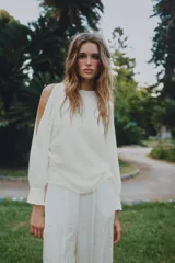 Blusa de cuello redondo y manga larga acabada en puño con frunces, detalle de aberturas en las mangas, frunces laterales y cierre trasero con abertura y botón.