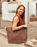 Bolso tipo tote de cuero vacuno color marrón caoba, con diseño artesanal que presenta costuras decorativas en el borde superior y asas fijas de hombro.