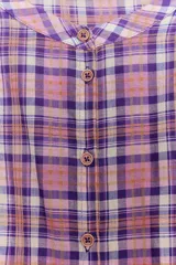 Blusa de cuello redondo y manga larga abullonada, con estampado de cuadros en tonos rosados, violetas y blancos. Cierre frontal con botones.