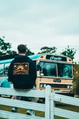 Hoodie negro con capucha y estampado en la espalda con la frase "Classy Waves" y un diseño de palmeras y sol.