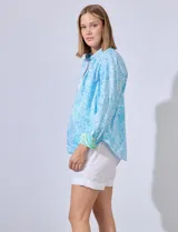 Camisa de algodón estampada en tonos celeste y blanco, con cuello con solapa, abertura central con botones y mangas largas con puños en contraste.
