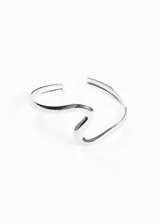 Brazalete rígido plateado con forma de ola, ajustable al brazo.