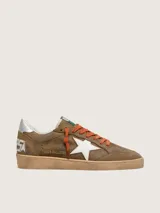 Zapatillas Golden Goose modelo Ball Star, confeccionadas en gamuza encerada marrón con efecto vintage. Tienen estrella lateral blanca, cordones naranjas, contrafuerte plateado en el talón y suela de goma con acabado envejecido.