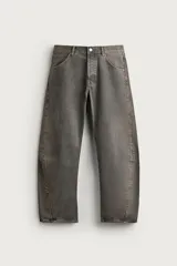 Jeans loose fit de hombre en denim de algodón color gris oscuro con efecto lavado. Presenta perneras con costuras giradas hacia los tobillos, tiro medio, cierre frontal con botones y bolsillos frontales con bolsillo cerillero.