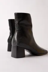 Bota de caña media con textura de reptil en color negro, punta cuadrada y taco bloque.