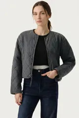 Campera corta acolchada de diseño matelasse con cierre frontal y cuello redondo. Presenta un corte recto y mangas largas.