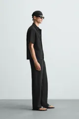 Camisa regular fit de manga corta confeccionada en tejido jacquard con estructura abierta y diseño geométrico. Presenta cuello solapa y cierre frontal con botones al tono.