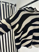 Sweater de punto con cuello alto y mangas murciélago, con estampado de cebra en blanco y negro.