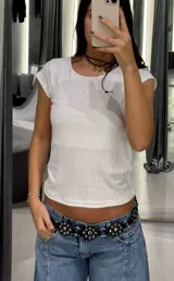 Top de tejido acanalado en color blanco, con cuello redondo y mangas cortas tipo casquillo.