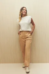 Pantalón color beige de tiro alto y corte recto, con bolsillos delanteros amplios con botones.