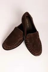 Mocasín de gamuza color bordó con detalle de frunces en la puntera y suela plana de goma negra.