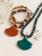 Collar de piedras naturales en tonos verdes y multicolores, con un gran dije de porcelana en forma de hoja en tono verde o naranja, unido mediante una argolla de acero.