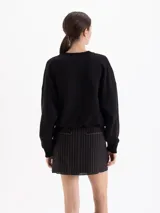 Buzo negro de corte holgado con cuello redondo, mangas largas y puños acanalados. Presenta un estampado central de una frutilla grande con detalles realistas.