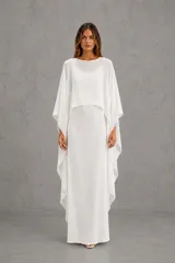Vestido largo de seda fría, color blanco, compuesto por un vestido base sin mangas y un chal superpuesto asimétrico con efecto capa.