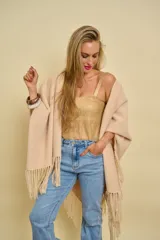 Ruana beige de lana con flecos en los extremos y diseño en picos en la espalda.