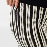 Pantalón de maternidad de corte recto y tiro alto, con estampado de rayas verticales en blanco y negro. Presenta cintura elástica diseñada para adaptarse al crecimiento de la panza durante el embarazo.
