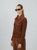 Chaqueta corta negra de pana de algodón con cuello clásico, cierre frontal con botones, dos bolsillos de parche en el pecho y mangas largas.