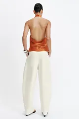 Top de cuello halter satinado en color naranja tostado, con espalda descubierta y cierre trasero de botones.
