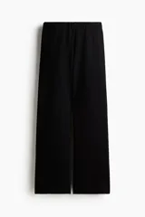 Pantalón negro de tejido liso, corte amplio y tiro alto con cintura elástica.