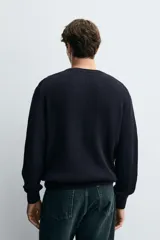 Sweater de punto en canalé color negro, de corte regular fit, cuello redondo y manga larga con terminaciones en rib.