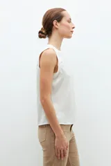 Blusa de satén color blanco, sin mangas, con cuello redondo y diseño fluido.